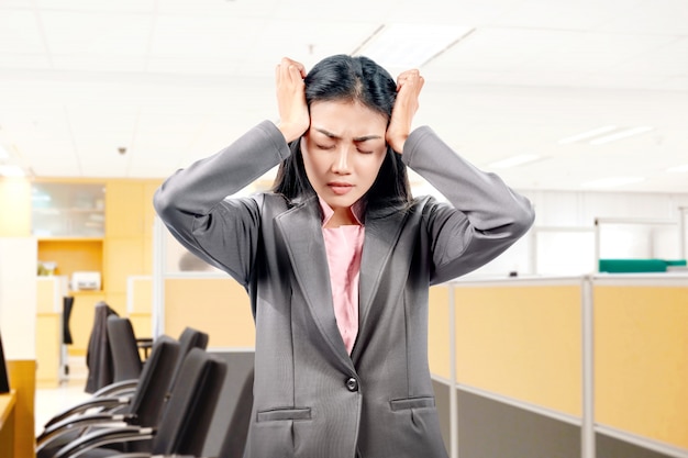 Femme d'affaires asiatique avec expression de maux de tête