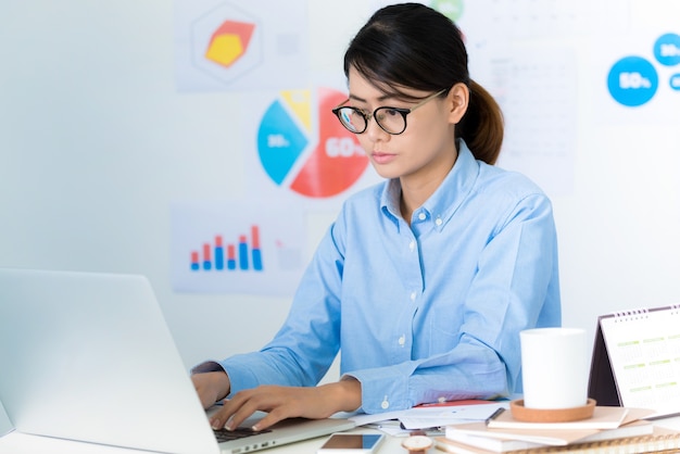 Une femme d&#39;affaires asiatique fait attention en travaillant - Concepts commerciaux et financiers.