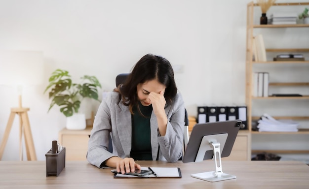 Femme d'affaires asiatique fatiguée avec des maux de tête au bureau se sentant malade au travail