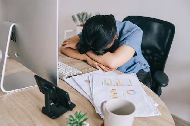 Une femme d'affaires asiatique fatiguée se sent malade et endormie au bureau.