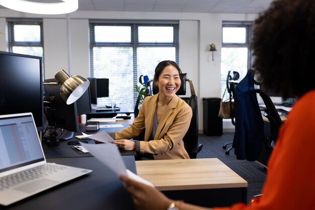 Une femme d'affaires asiatique heureuse au bureau parle à une collègue au bureau. Affaires, emploi, entreprise, coopération et travail au bureau.