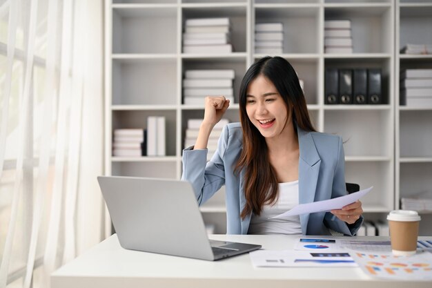 Femme d'affaires asiatique joyeuse célébrant le succès de son projet ou obtenant une promotion