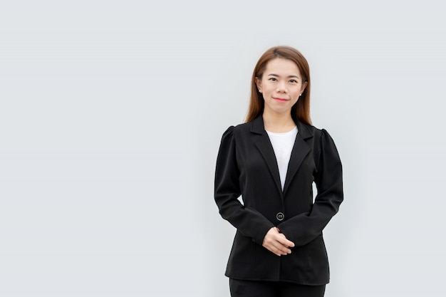 Femme d'affaires asiatique mains croisées debout avec les cheveux longs en costume noir isolé sur blanc