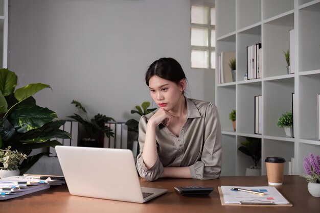 Une femme d'affaires asiatique malheureuse montre du stress alors qu'elle travaille dans un bureau à domicile décoré avec des produits apaisants