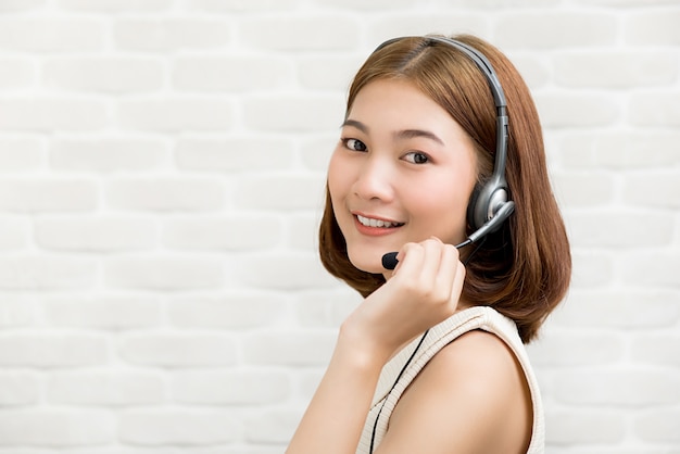 Femme d'affaires asiatique occasionnelle portant un micro-casque en tant qu'agent de service à la clientèle en télémarketing