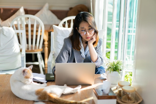 Femme d'affaires asiatique pensant pour des idées et utilisant un ordinateur portable travaillant sur le bureau dans le café