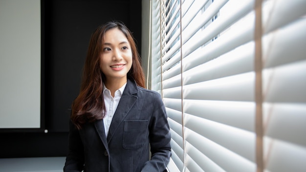 Femme d'affaires asiatique professionnelle debout souriant en toute confiance au bureau