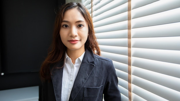 Femme d'affaires asiatique professionnelle debout souriant en toute confiance au bureau