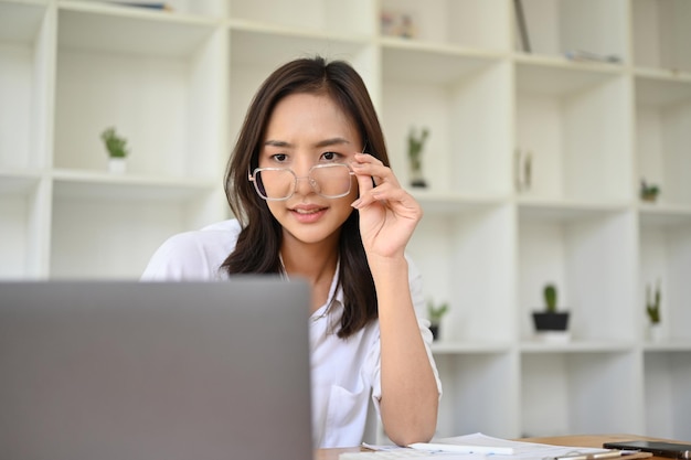 Femme d'affaires asiatique professionnelle portant des lunettes regardant un écran d'ordinateur portable