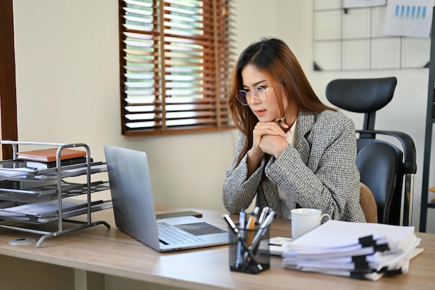 Femme d'affaires asiatique se concentrant sur l'analyse de ses données de vente comptable sur ordinateur portable