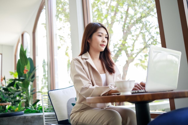 Femme d'affaires asiatique séduisante travaillant par ordinateur portable dans le café Femme confiante et intelligente et concept d'entreprise