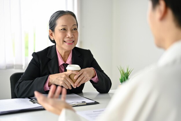 Une femme d'affaires asiatique senior ou une recruteuse interviewe un candidat masculin au bureau