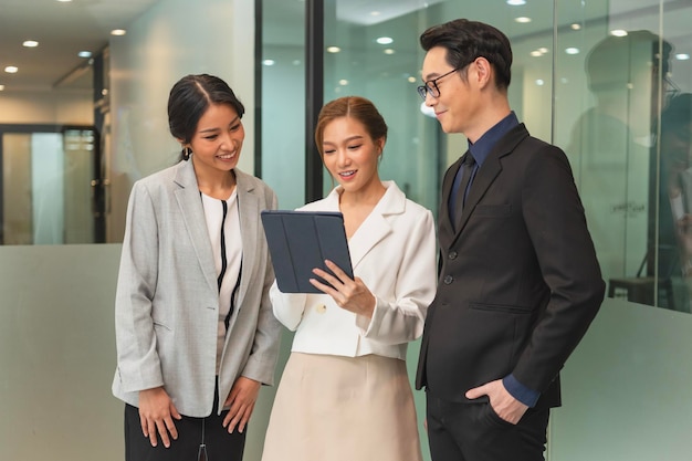 Femme d'affaires asiatique souriante montrant une tablette à son manager lors d'une conversation au bureau