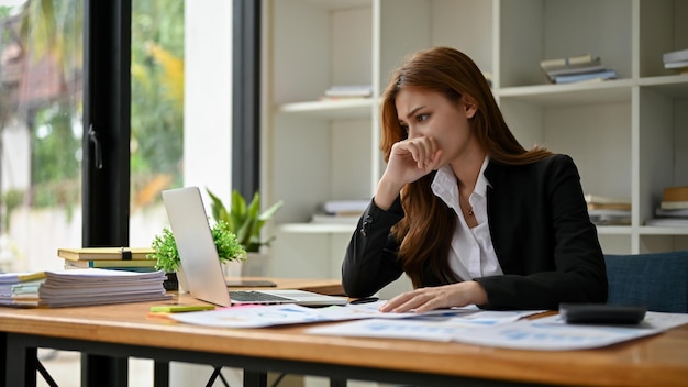 Une femme d'affaires asiatique stressée analysant les données financières de l'entreprise sur son ordinateur portable