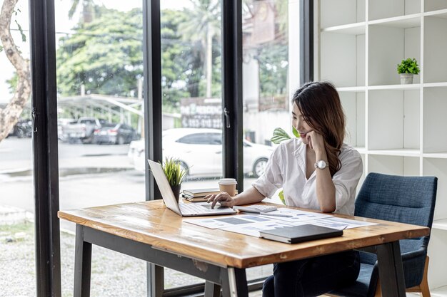 Femme d'affaires asiatique tapant un ordinateur portable dans son bureau privé, elle utilise son ordinateur portable pour taper, envoyer des messages professionnels avec un partenaire, elle utilise la messagerie Internet. Concept de femme d'affaires asiatique.