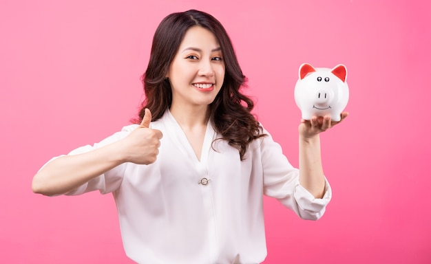 Femme d'affaires asiatique tenant piggy dans sa main, concept d'économie d'argent