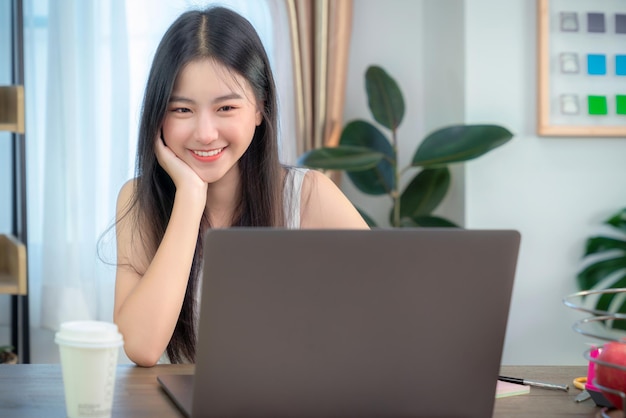 Une femme d'affaires asiatique travaillant dans un bureau à domicile sur la table avec un carnet d'ordinateur et une tasse de café