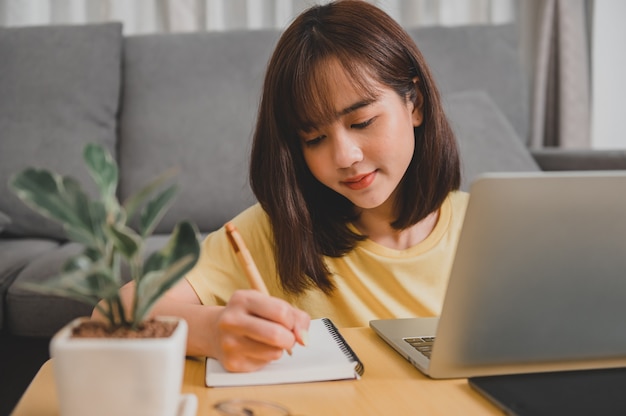 Femme d'affaires asiatique travaillant en ligne seule à la maison. Mode de vie de femme dans le salon. Distanciation sociale et nouvelle normalité.