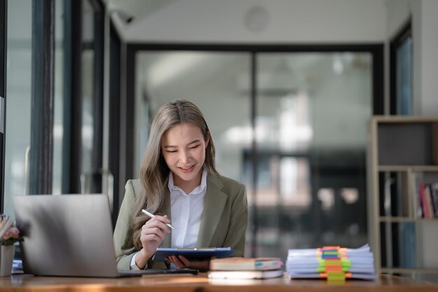 Une femme d'affaires asiatique travaille en utilisant son ordinateur portable en tapant dans le bureau.