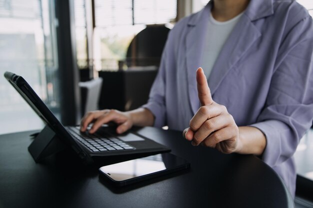 Une femme d'affaires asiatique utilisant une calculatrice et un ordinateur portable pour faire des finances mathématiques sur un bureau de bureau rapport fiscal statistiques comptables et concept de recherche analytique