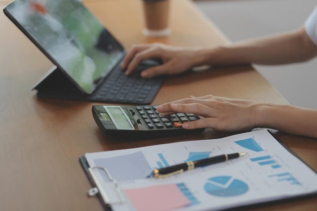 Femme d'affaires asiatique utilisant une calculatrice et un ordinateur portable pour faire des finances mathématiques sur un rapport fiscal de bureau statistiques comptables et concept de recherche analytique