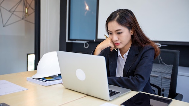 Femme d'affaires asiatique utilisant un ordinateur portable pour travailler et faire des recherches sur Internet dans son bureau