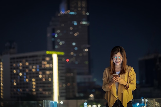 Femme d'affaires asiatique utilisant un téléphone mobile intelligent avec action de sourire dans le quartier financier
