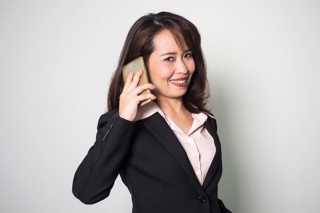 Femme d&#39;affaires asiatiques à l&#39;aide d&#39;un téléphone intelligent. Souriant et regardant la caméra.