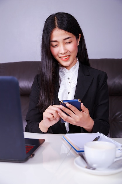 femme d&#39;affaires assis au bureau et à l&#39;aide de téléphone portable