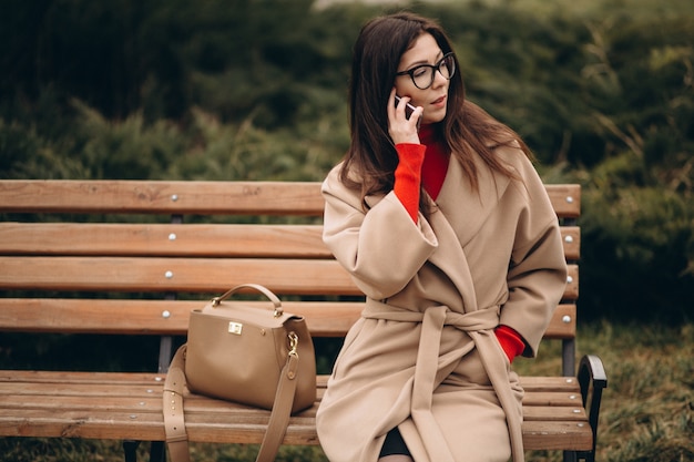 Femme d&#39;affaires assis sur un banc et parler au téléphone