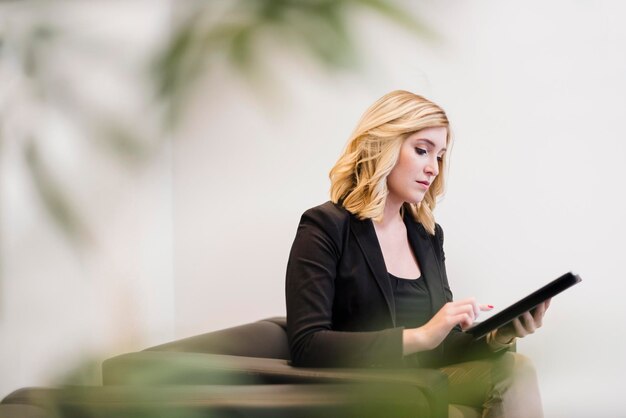 Femme d'affaires assise sur un canapé à l'aide d'une tablette