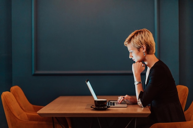 Une femme d'affaires assise dans un café tout en se concentrant sur son ordinateur portable et en participant à une réunion en ligne Focus sélectif Photo de haute qualité