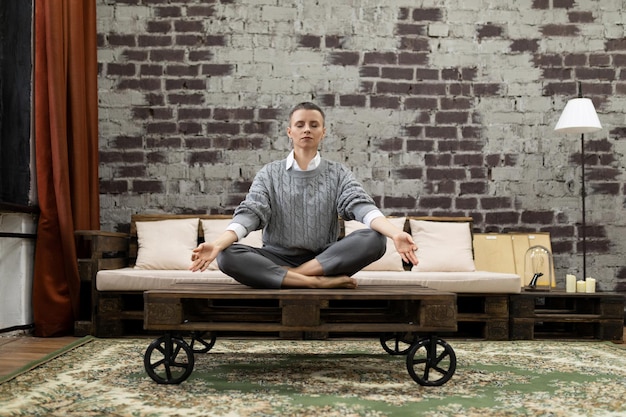 Femme d'affaires assise dans une pose de yoga à la maison au travail à distance