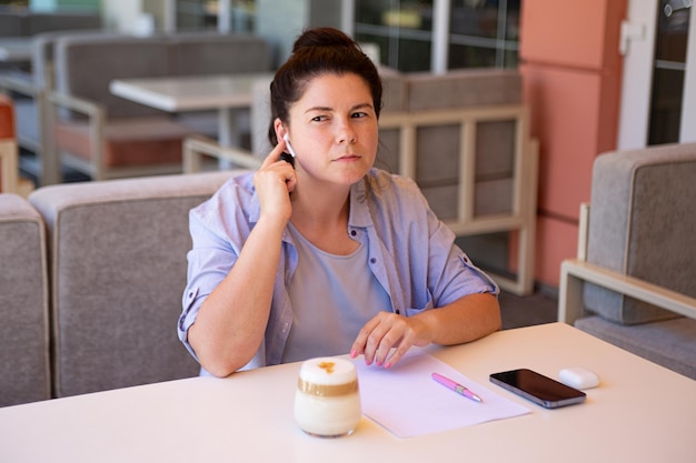 Femme d'affaires assise dehors avec son téléphone portable et un document vierge avec un casque sans fil