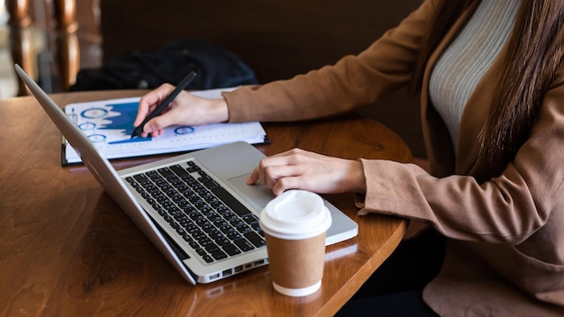 Femme d'affaires assise devant un ordinateur portable tablette avec des graphiques financiers et des statistiques sur monitorat officexA