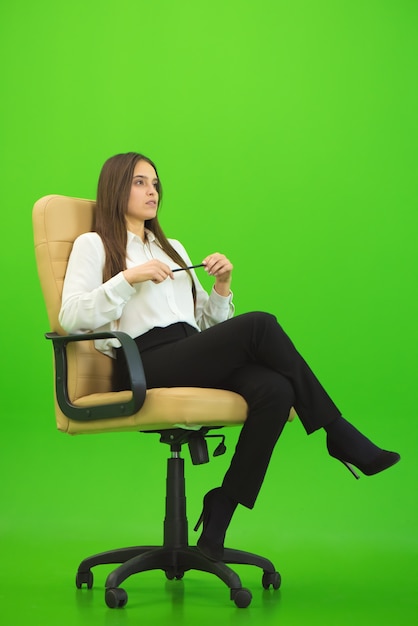 La femme d'affaires assise sur le fond vert