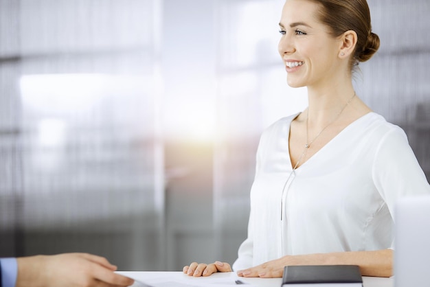 Femme d'affaires assise et regardant la caméra dans un bureau ensoleillé. Notion d'entreprise