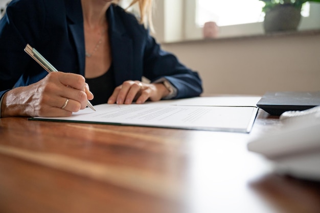 Femme d'affaires assise à son bureau, signant un contrat