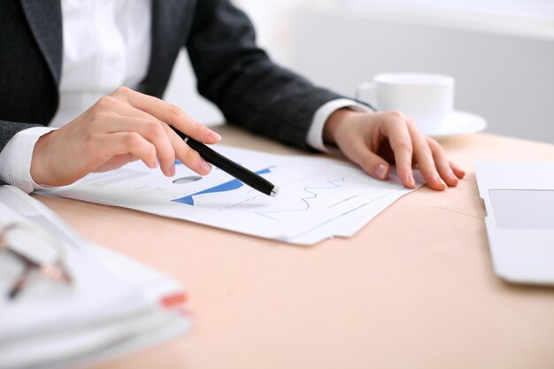 Femme d'affaires assise à la table et examine les résultats financiers