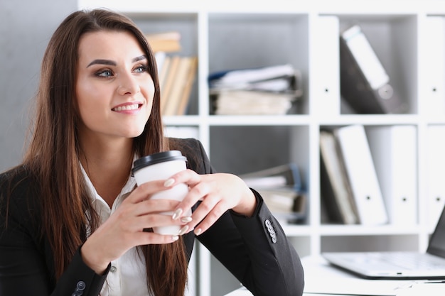 Femme d'affaires au lieu de travail au bureau portrait pendant la pause boit du café de tasse blanche