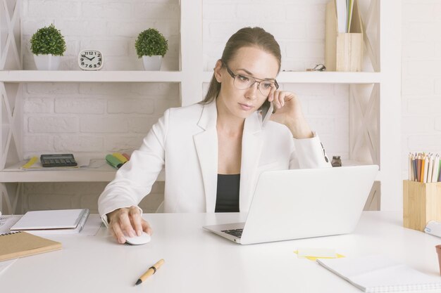 Femme d'affaires au téléphone à l'aide d'un ordinateur portable