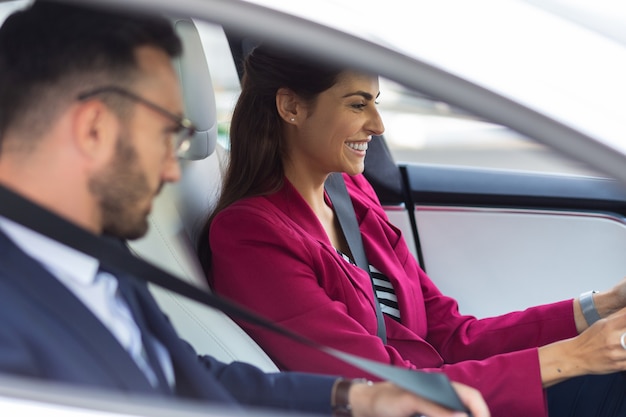 Femme d'affaires au volant. Belle femme d'affaires élégante souriante en conduisant une voiture avec son mari assis à proximité