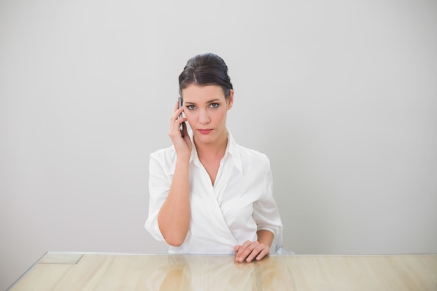 Femme d&#39;affaires aux cheveux brun sérieux au téléphone