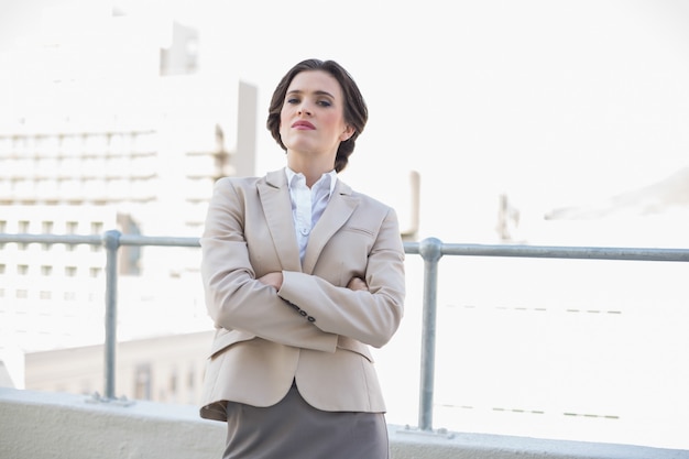 Femme d&#39;affaires aux cheveux bruns attrayant debout avec les bras croisés