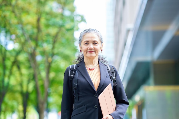 Une femme d'affaires aux cheveux gris souriante qui sort.