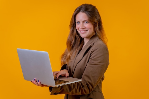 Femme d'affaires aux yeux bleus sur fond jaune avec un ordinateur