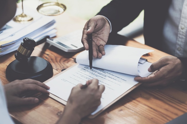 Femme d'affaires et avocats discutant des documents contractuels avec une échelle en laiton sur un bureau en bois au bureau Conseil des services juridiques juridiques Concept de justice