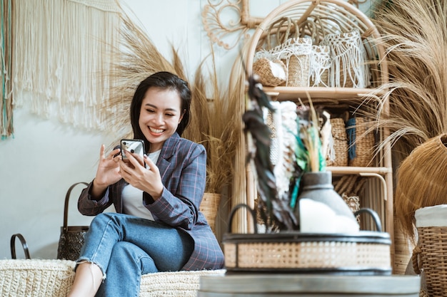 Femme d'affaires en blazer à l'aide d'un smartphone dans une boutique d'artisanat sur un artisanat fait main