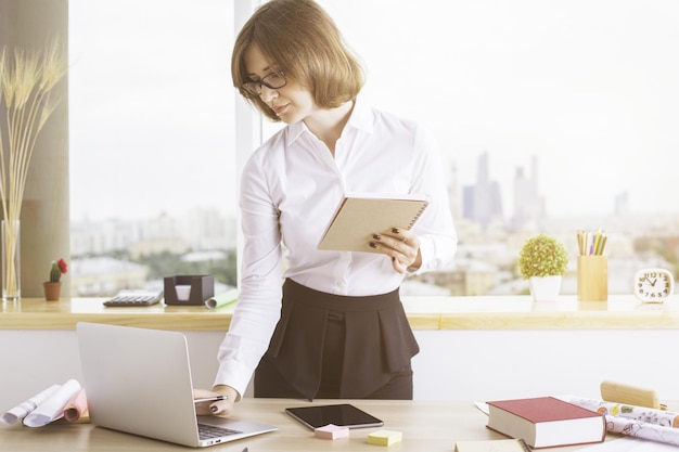 Femme d'affaires avec bloc-notes à l'aide d'un ordinateur portable