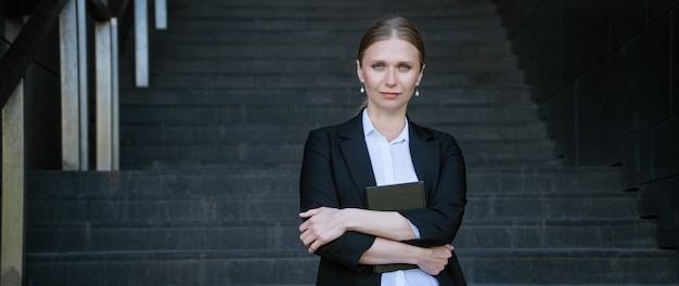 Femme d'affaires avec le bloc-notes à la main en cavalier noir sur les marches